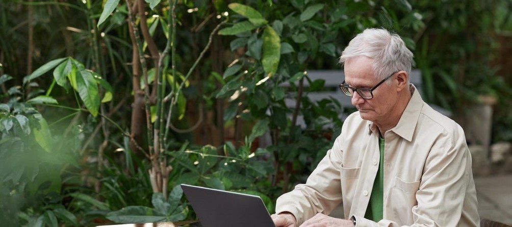 Man at his laptop outside in a garden